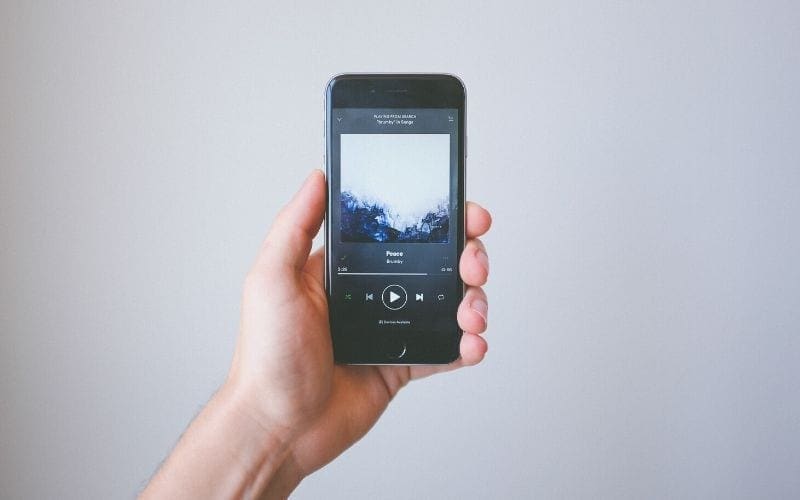 person holding iPhone with Spotify music streaming