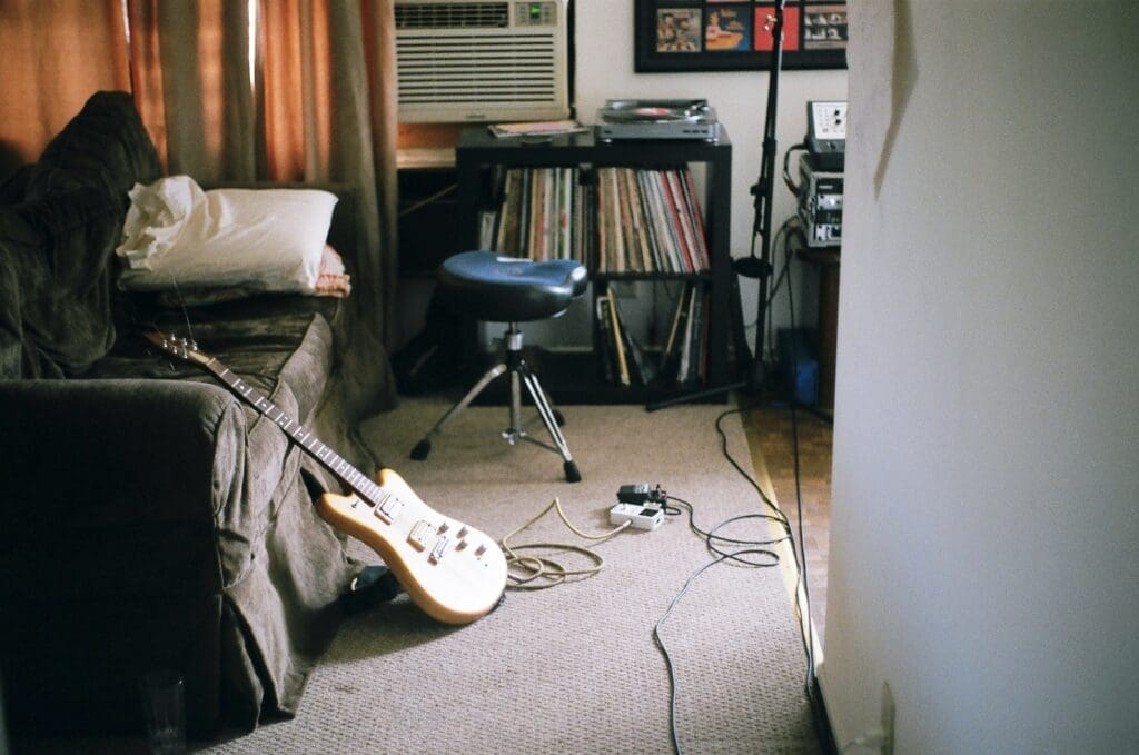 Guitar leaning aganast a sofa ready to play